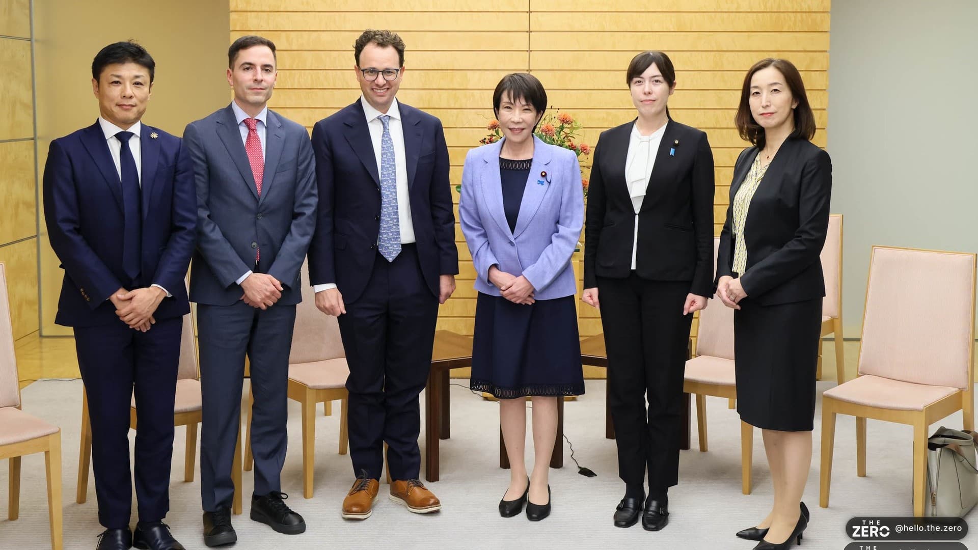 Grupo em pé diante da parede de madeira do gabinete da primeira-ministra do Japão, em 29 de outubro de 2025: Dario Amodei, de óculos e gravata azul, é o terceiro a partir da esquerda, e Sanae Takaichi, de jaqueta lilás, está no centro