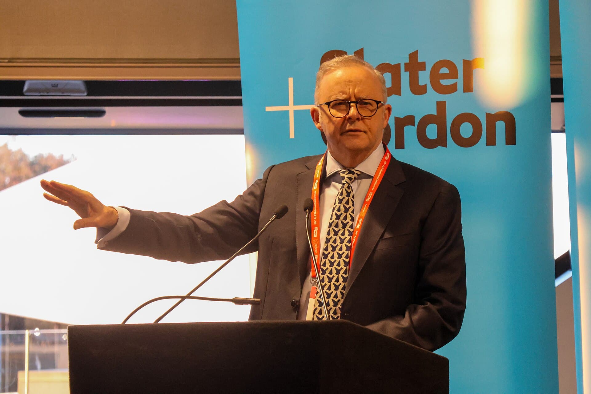 Anthony Albanese ao microfone num púlpito, com bandeiras da Austrália ao fundo, na Conferência Nacional do Partido Trabalhista em Adelaide