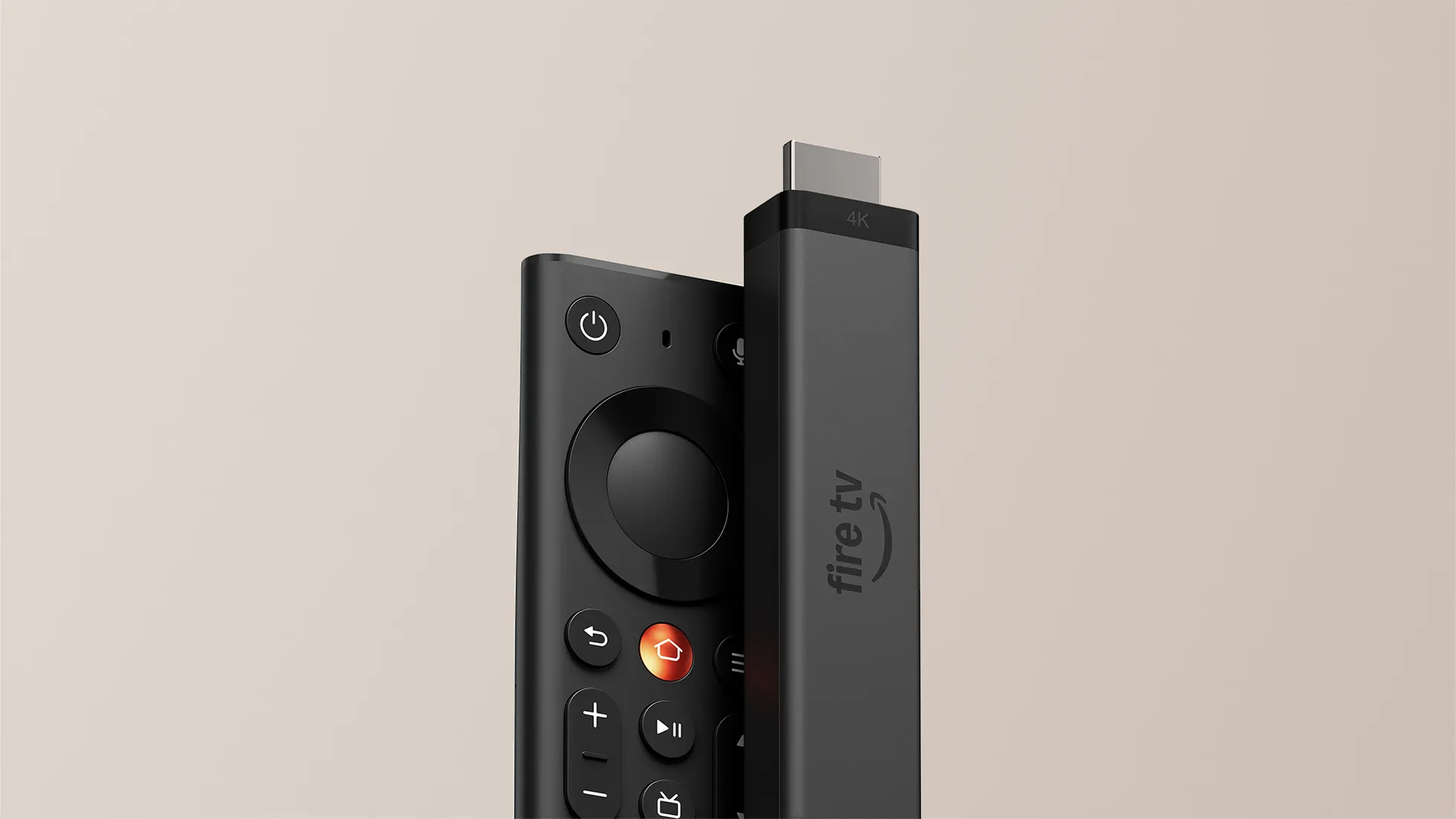 Dongle Fire TV Stick 4K em pé com conector HDMI visível no topo e logotipo fire tv na lateral fosca escura, apoiado ao lado do novo controle remoto Fire TV preto com botão Home metálico em tom cobre avermelhado, direcional circular e botões em relevo sobre fundo bege claro