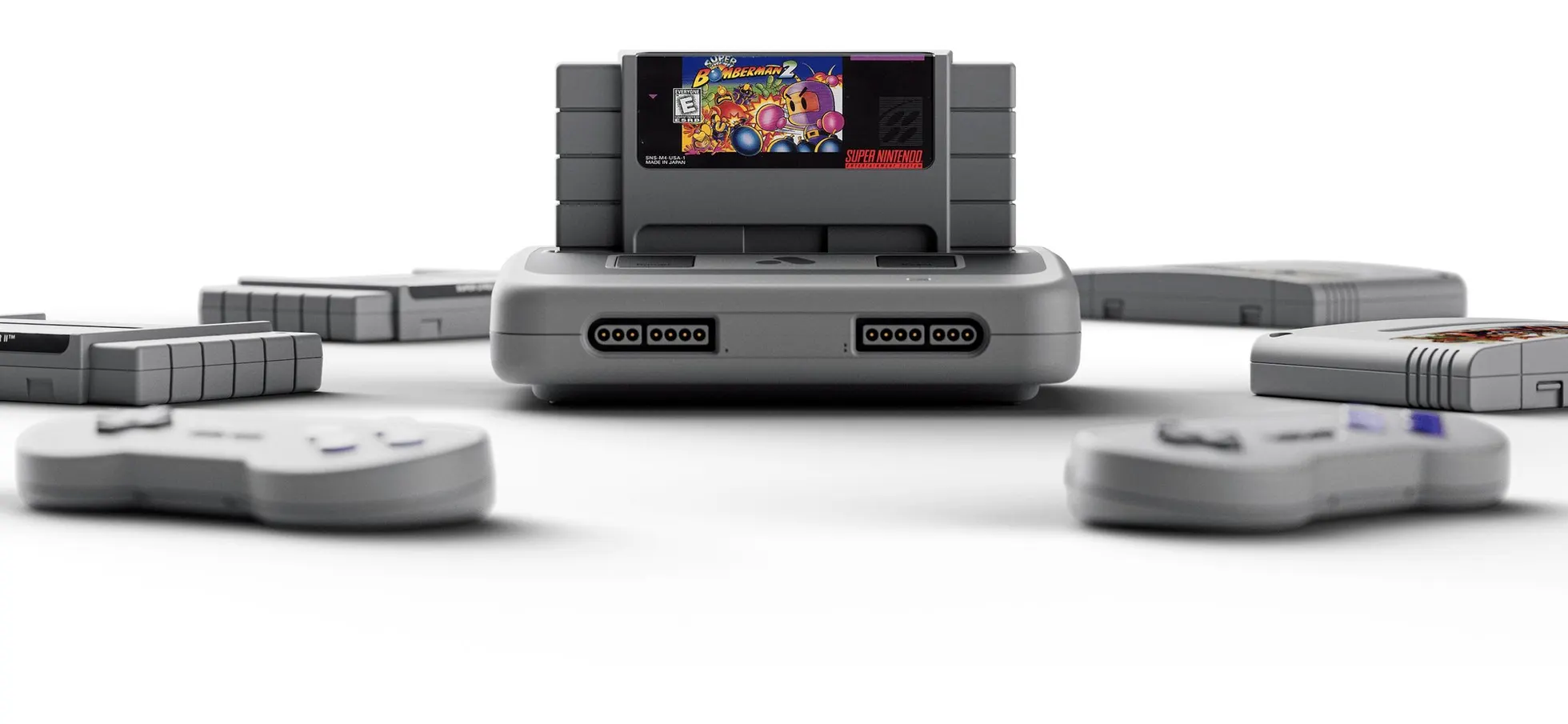 Console Analogue Super Nt cinza claro com cartucho de Super Bomberman 2 inserido no topo, ladeado por cartuchos e dois controles sem fio desfocados à frente sobre fundo branco