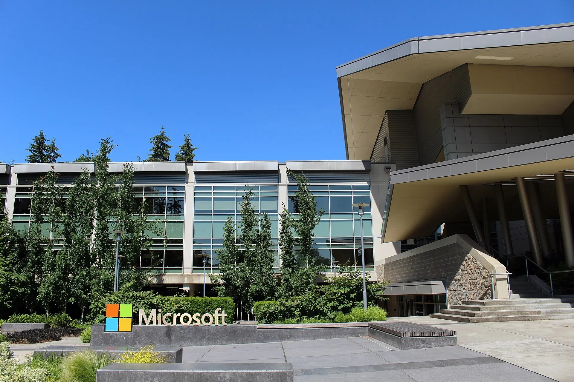 Prédio 92 da sede da Microsoft em Redmond, com o logotipo da empresa em primeiro plano e céu azul