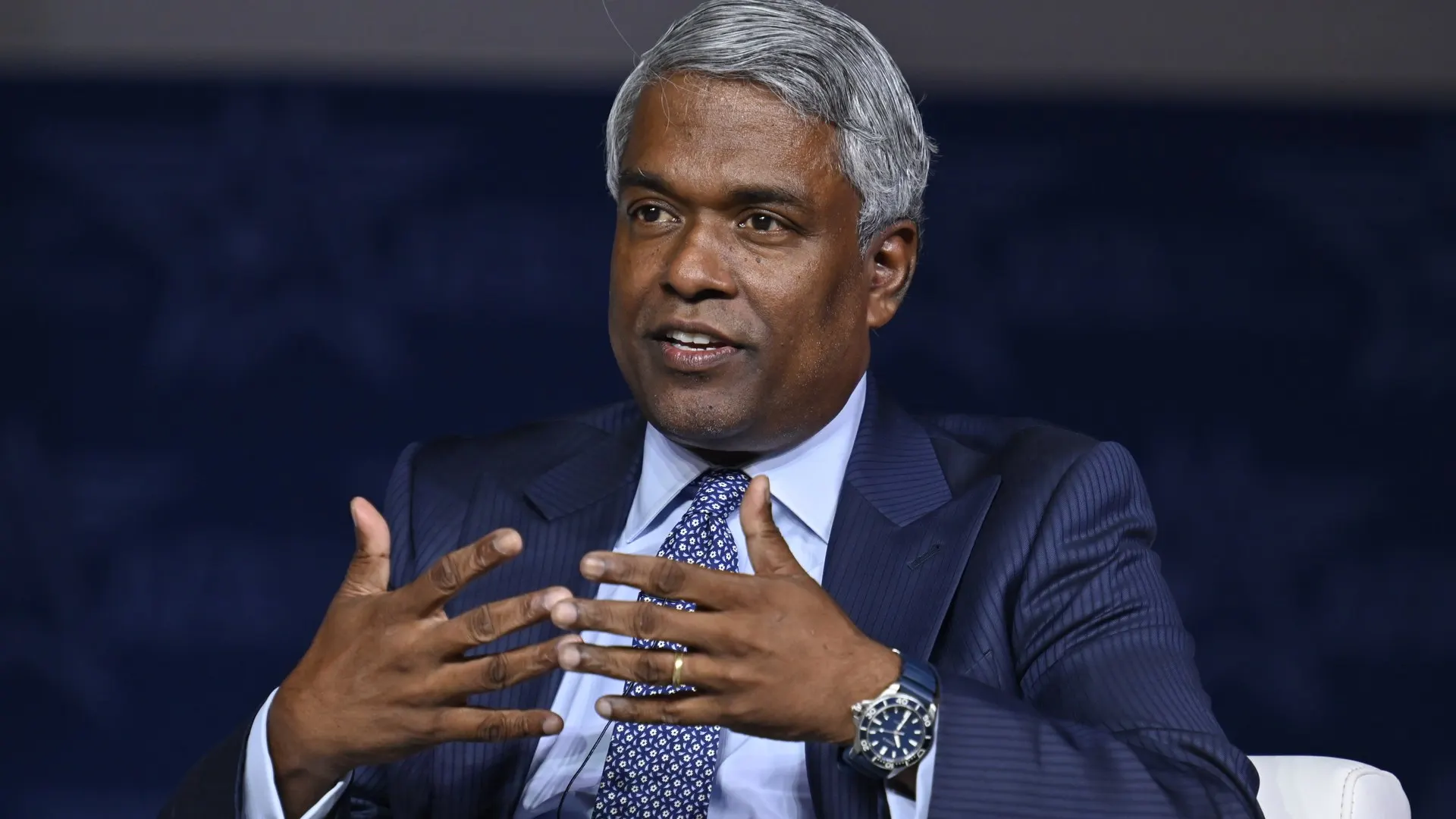 Thomas Kurian, presidente-executivo do Google Cloud, gesticula durante conversa em palco, de terno azul e gravata estampada