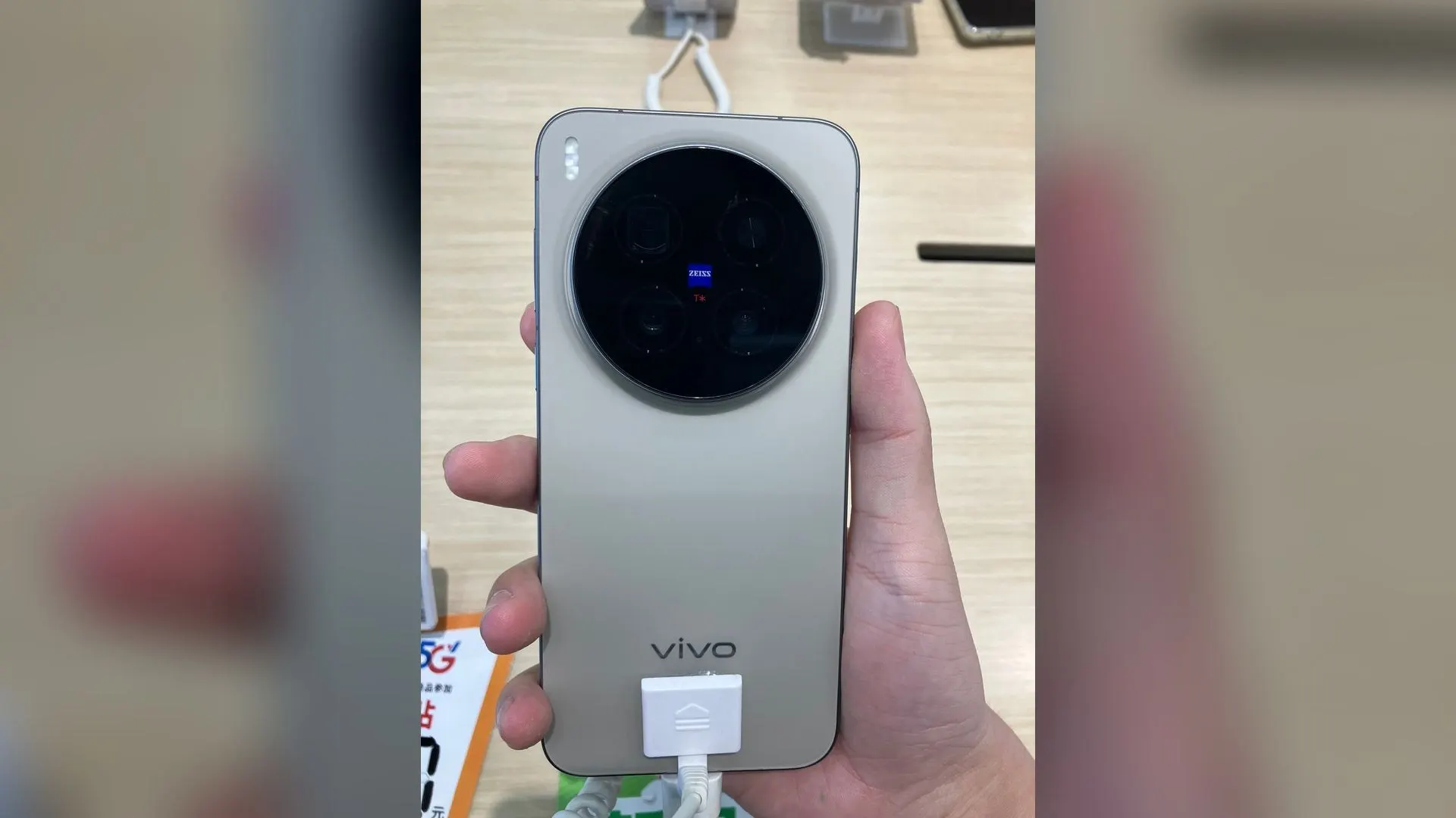 Traseira de um celular Vivo X300 Pro com módulo de câmera circular Zeiss, segurado em uma loja. Foto ilustrativa do modelo anterior, não é a linha X500