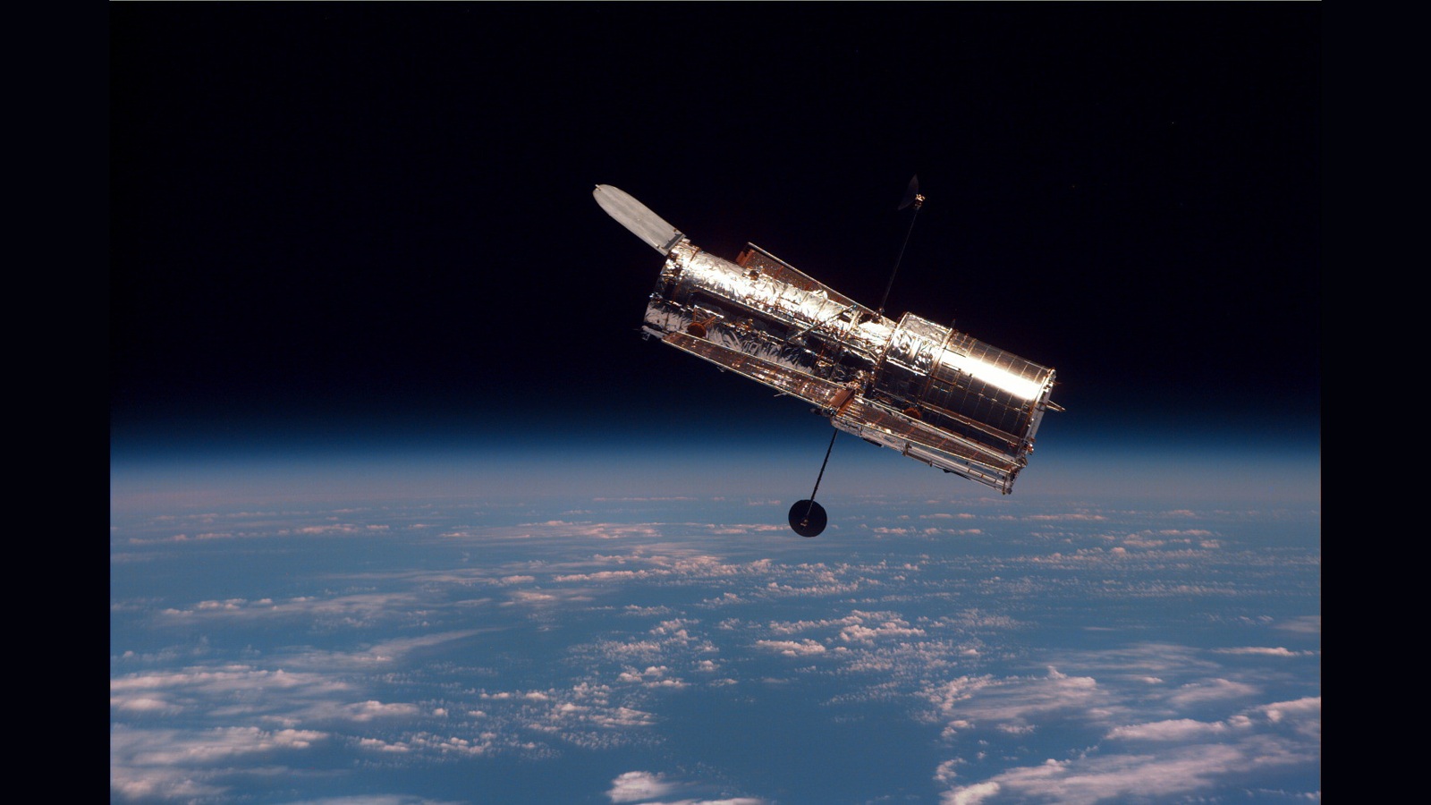 Telescópio cilíndrico prateado acima da Terra com nuvens, antenas estendidas e fundo escuro