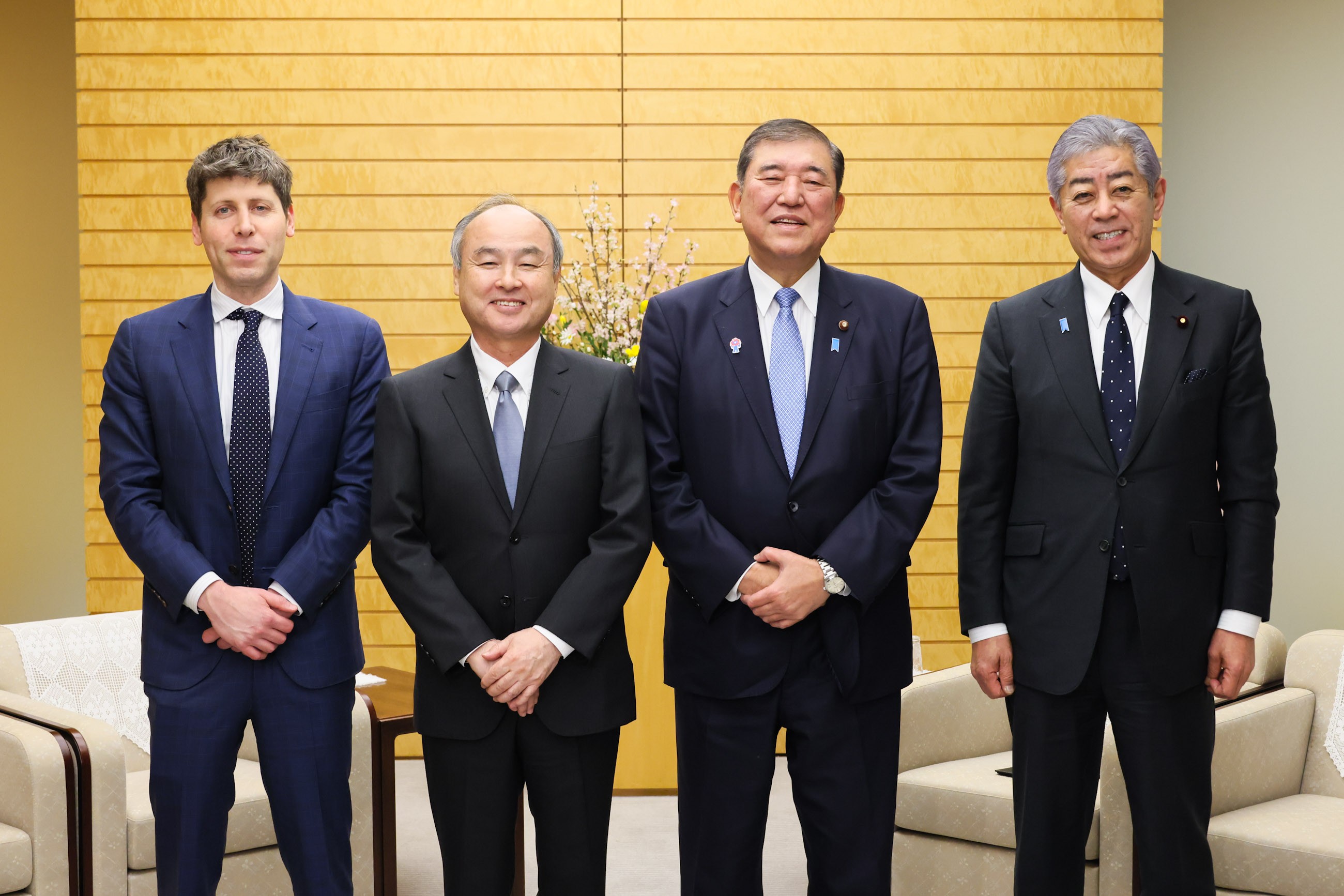 Três homens de terno sentados a uma mesa de madeira na residência do primeiro-ministro do Japão, com bandeiras japonesas ao fundo, no encontro de 3 de fevereiro de 2025 entre Shigeru Ishiba, Masayoshi Son e Sam Altman